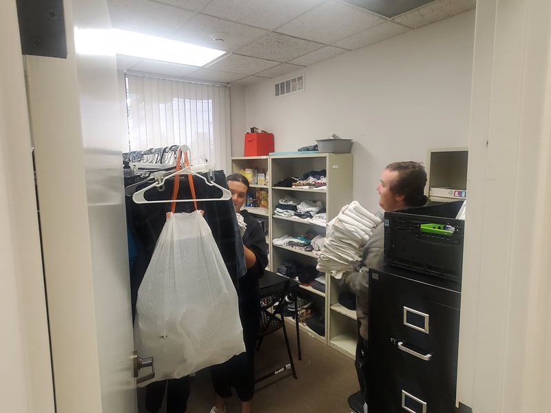 Two ABLED clients putting folded towels away in the Retail room