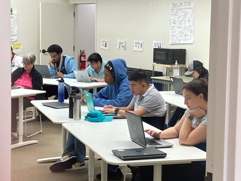 A group of ABLED clients working on classwork in the classroom, using their computers