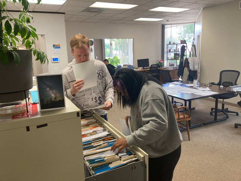 Two ABLED clients filing papers in a filing cabinet